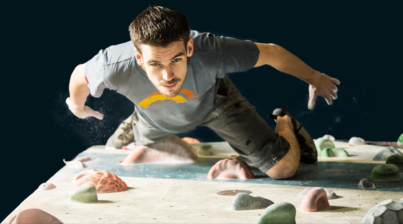 Man looking up, deciding his next move on the wall at The Climbing Hangar
